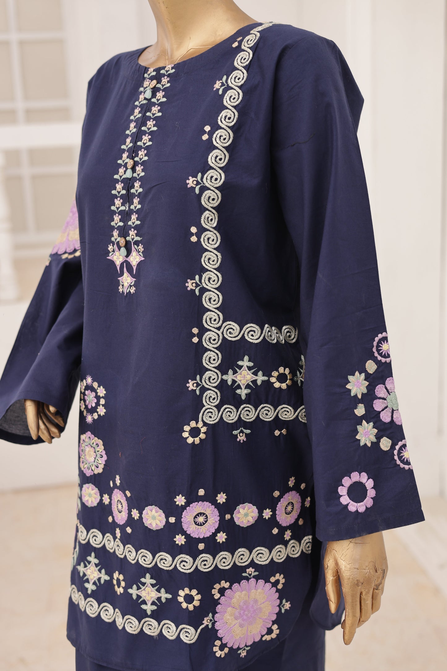 Navy blue dress with intricate white embroidery on a mannequin against a neutral background