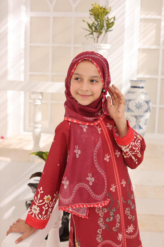 Young girl wearing a red embroidered outfit with a matching hijab in a bathroom setting.