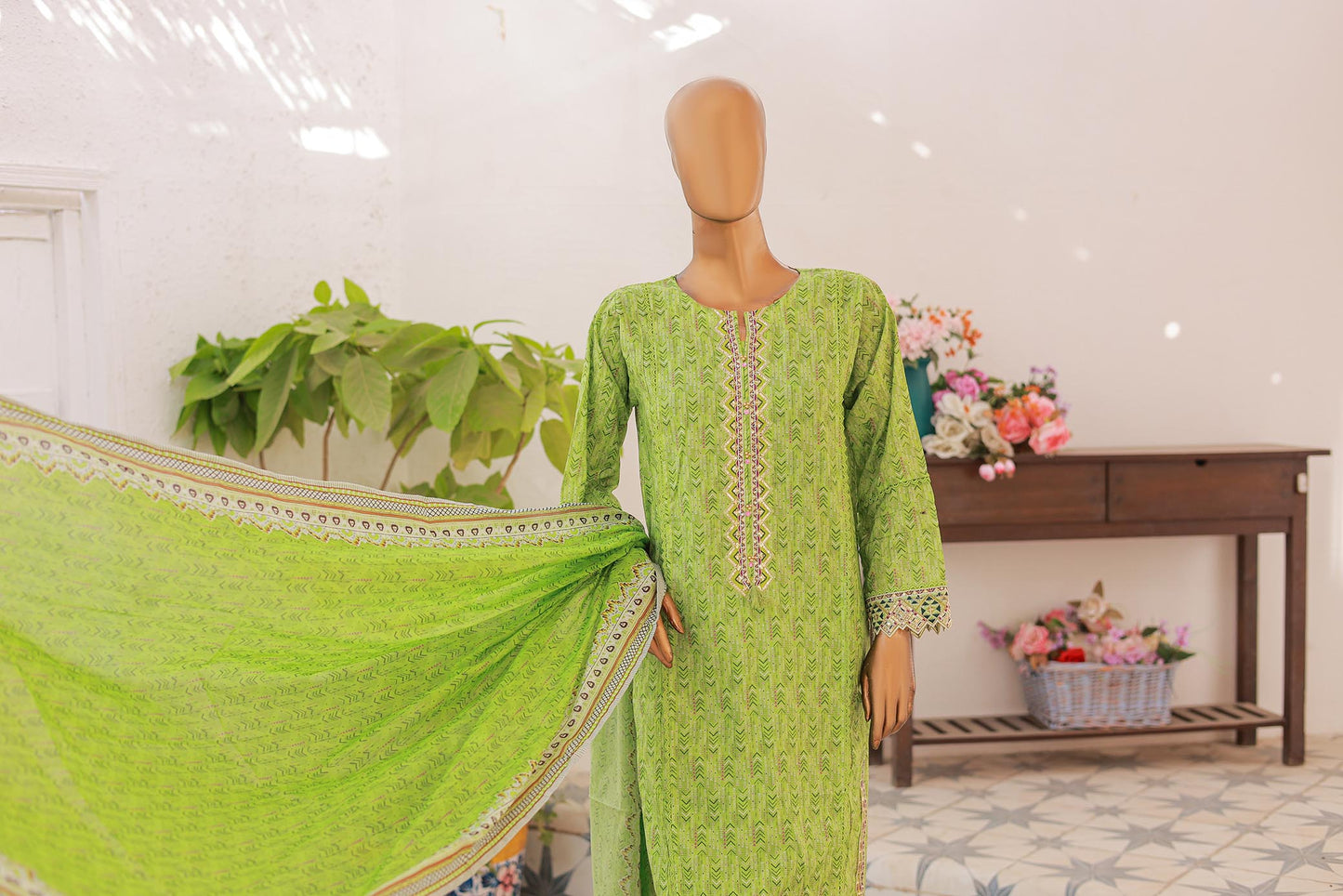 Mannequin wearing a green traditional outfit with a matching dupatta in a well-lit room.