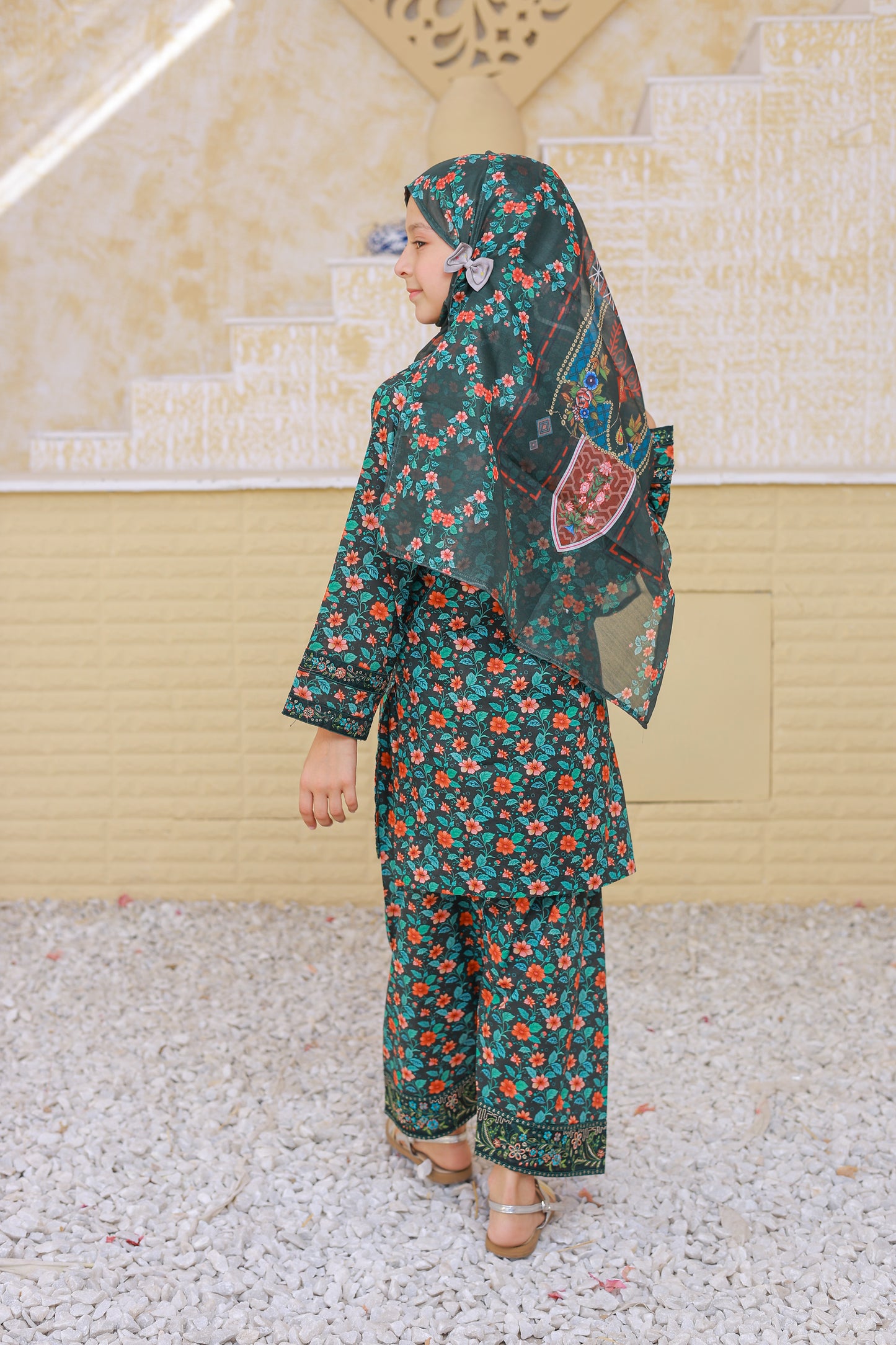 Woman wearing a floral outfit with a matching headscarf in an outdoor setting.