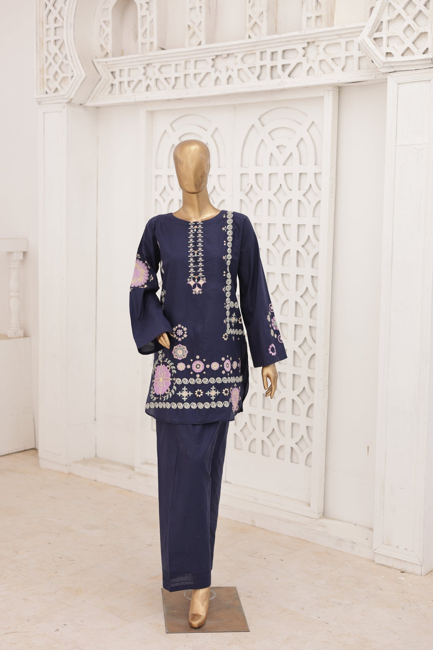 Navy blue embroidered outfit on a mannequin against a white decorative wall.