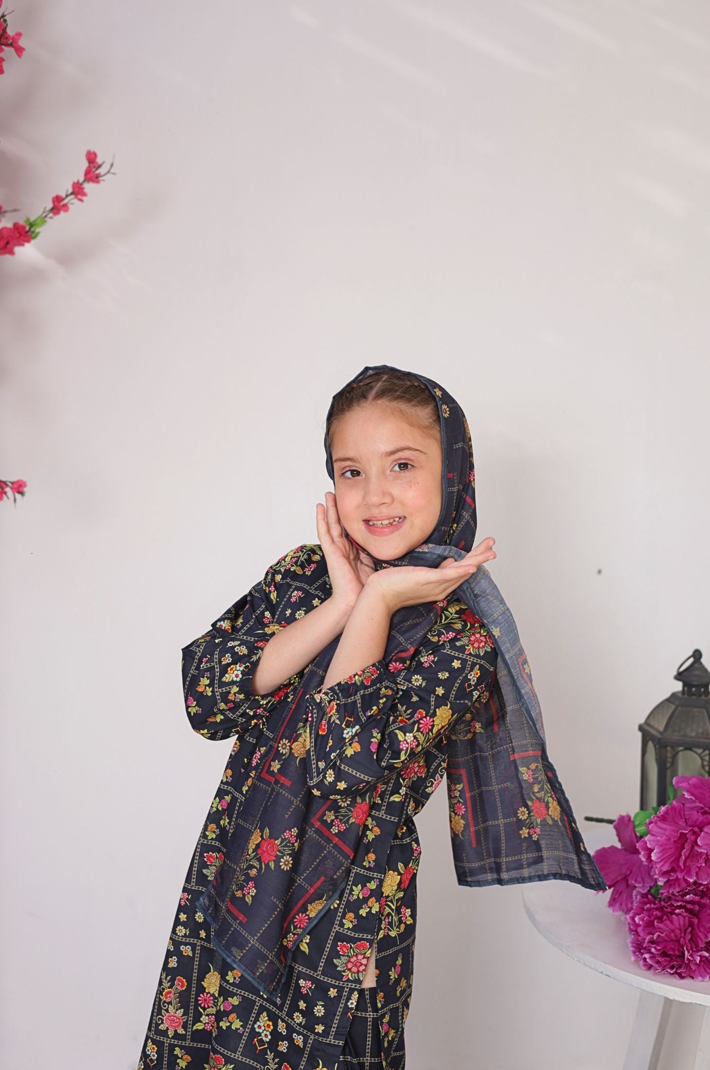 Young girl wearing a floral dress with a hood against a white background