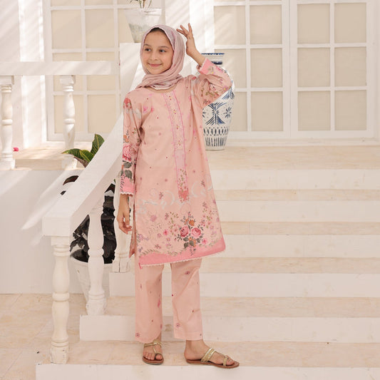 Young girl in a pink floral outfit standing in a bright, white interior setting.