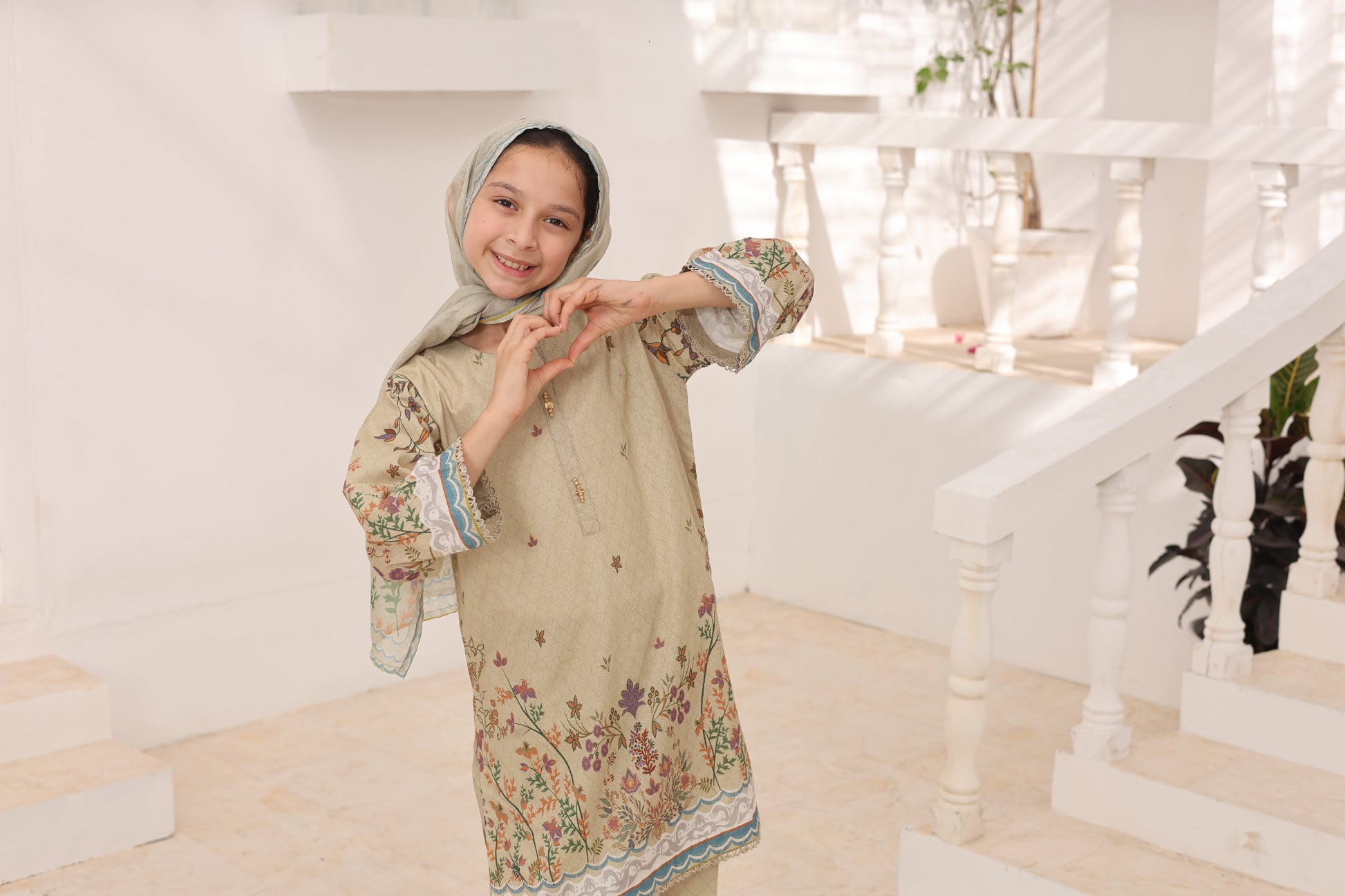Young girl in a floral dress standing in a white interior setting