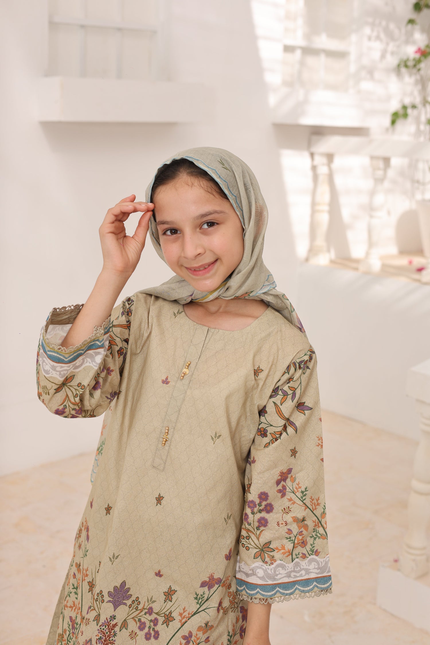 Young girl wearing a floral dress and headscarf in a bright indoor setting
