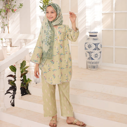 Woman in a light green outfit with floral patterns standing on a white floor with decorative plants.