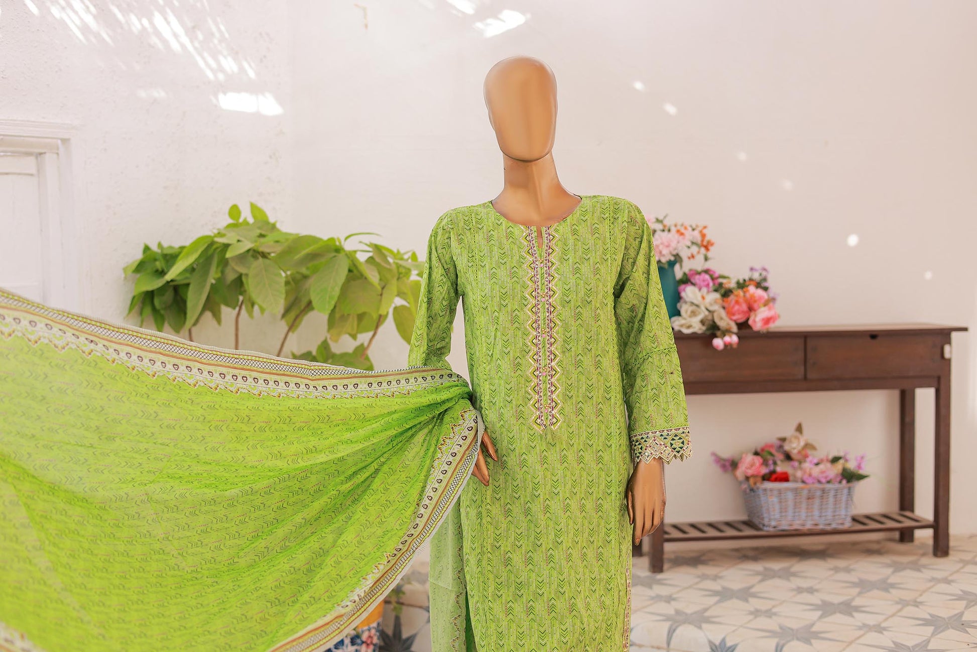 Mannequin wearing a green traditional outfit with a matching dupatta in a well-lit room.