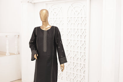 Black dress on a mannequin against a white wall with decorative patterns