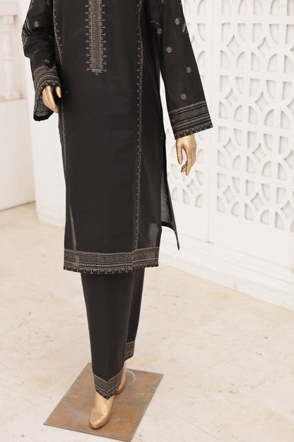 Person wearing black pants with gold accents on a white textured surface