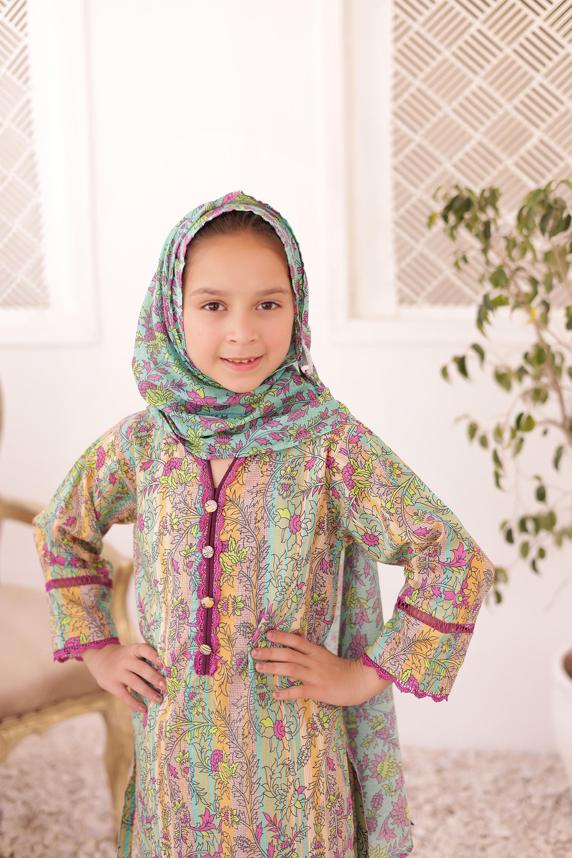 Young girl wearing a colorful traditional outfit with a headscarf indoors.