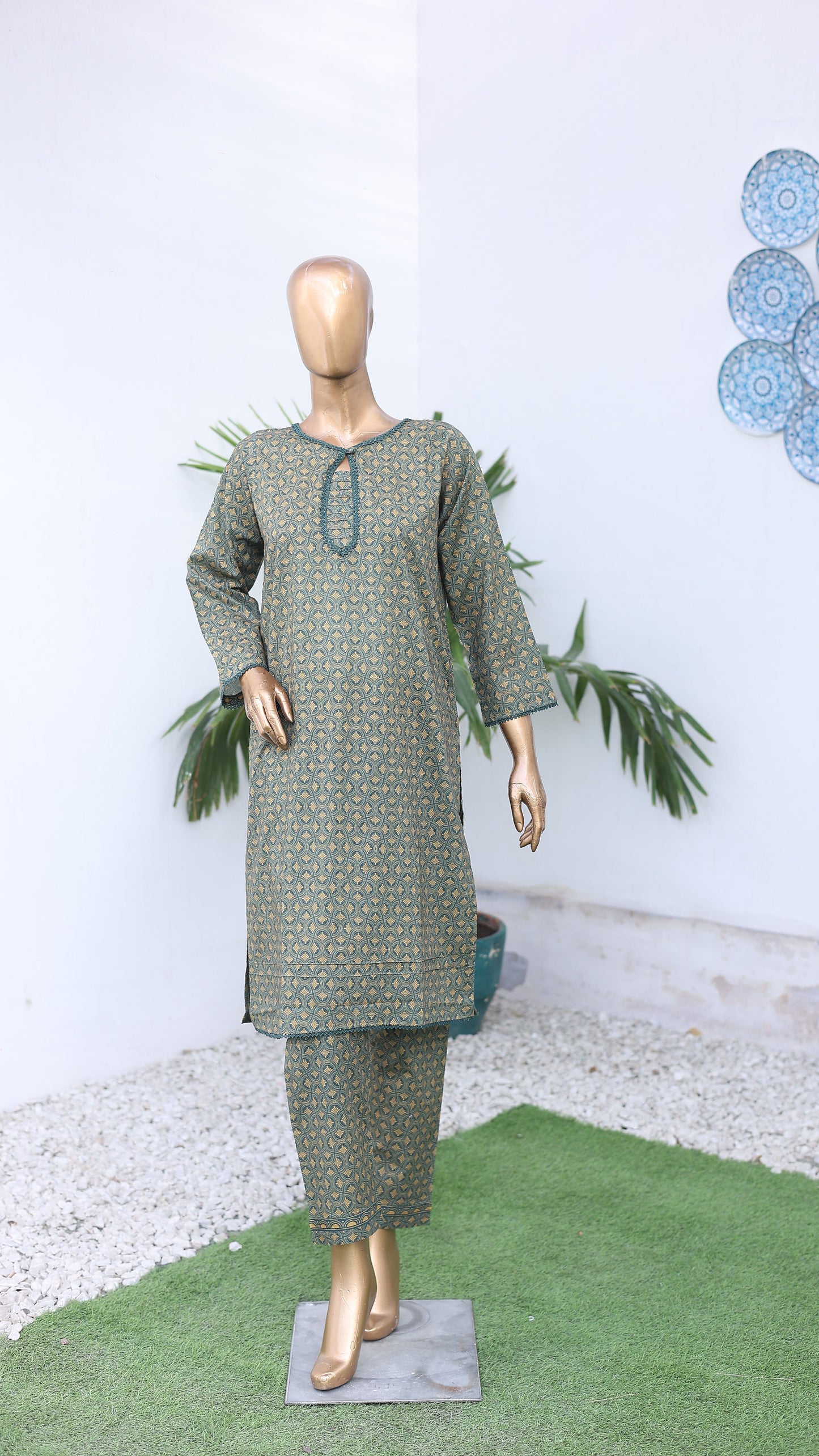 Mannequin wearing a green patterned dress with decorative elements on a white background