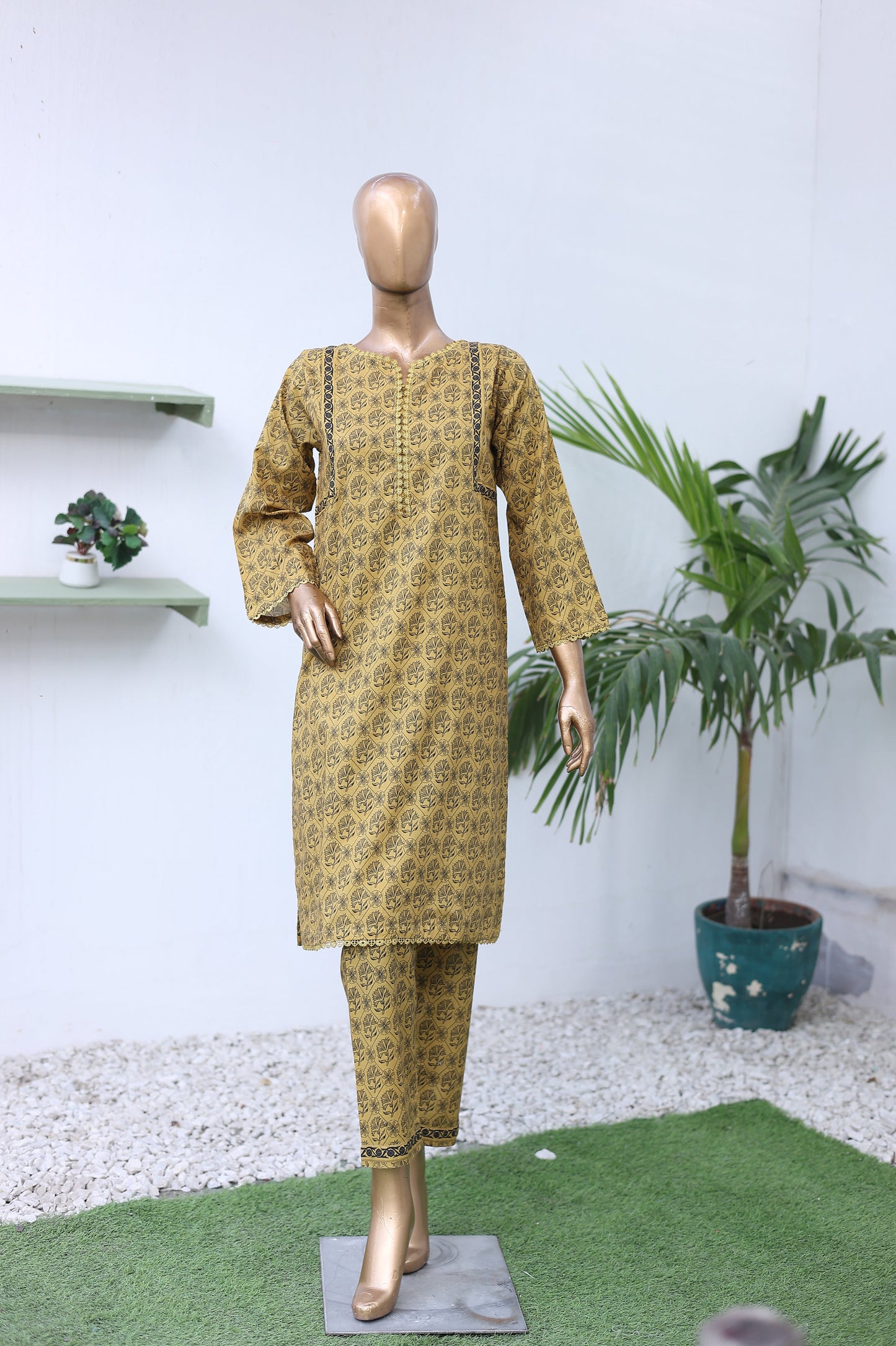 Mannequin wearing a patterned dress on a white background with a plant.
