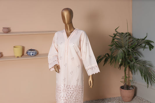 Mannequin wearing a white lace dress against a beige wall with decorative items and a plant.