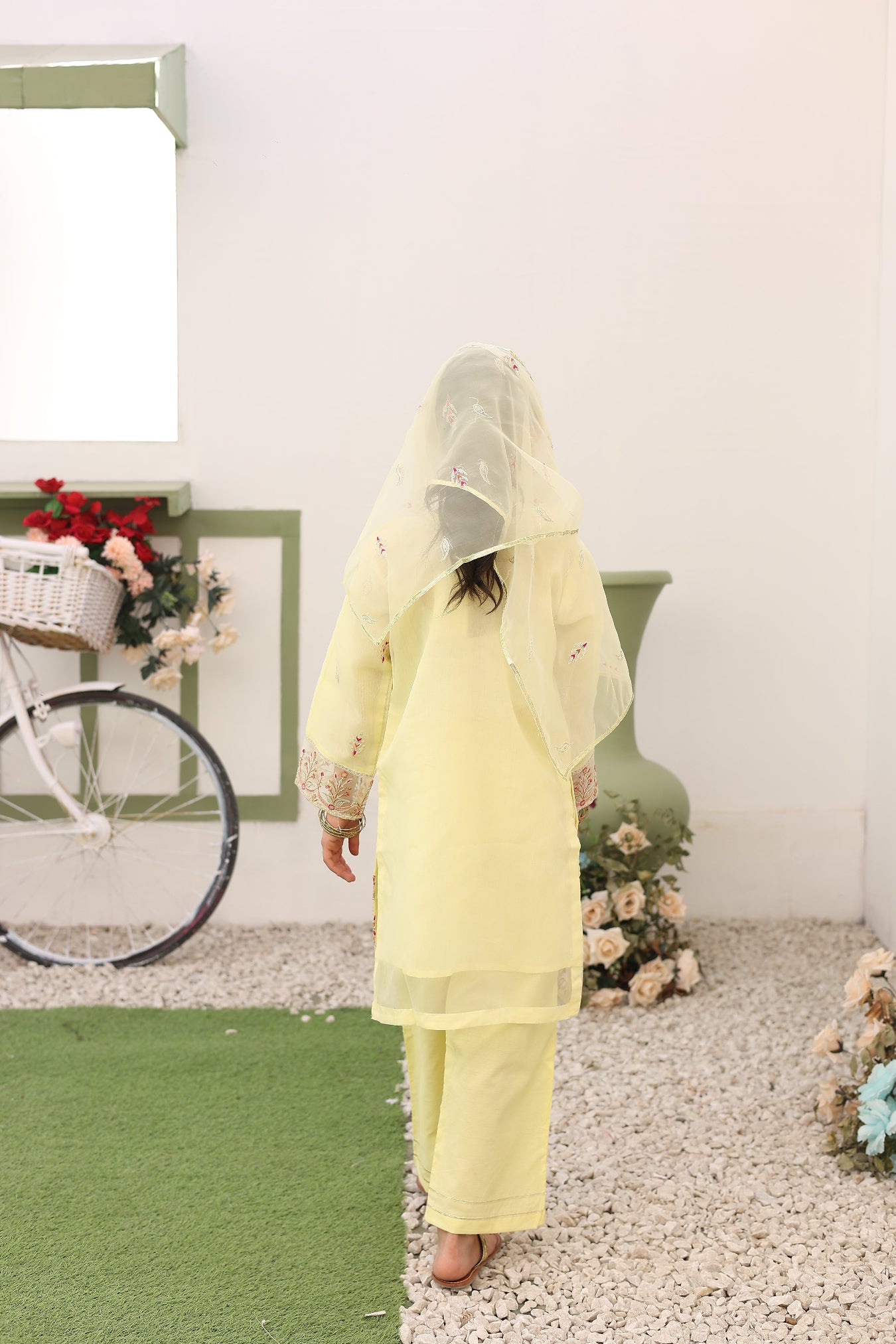 Person wearing a yellow raincoat with a bicycle and flowers in the background