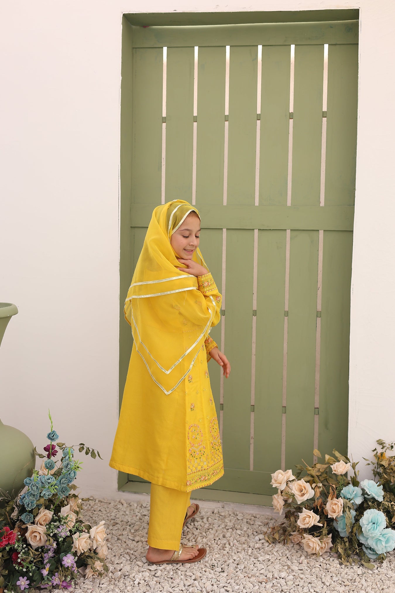 Person wearing a yellow outfit with floral decorations on a white background