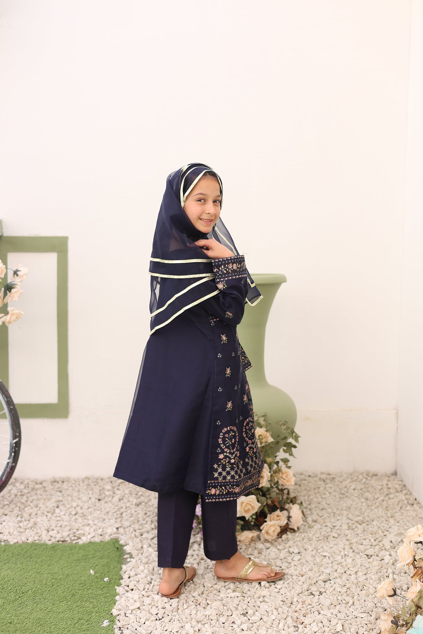 Woman in a navy outfit with white patterns standing on a carpeted floor.