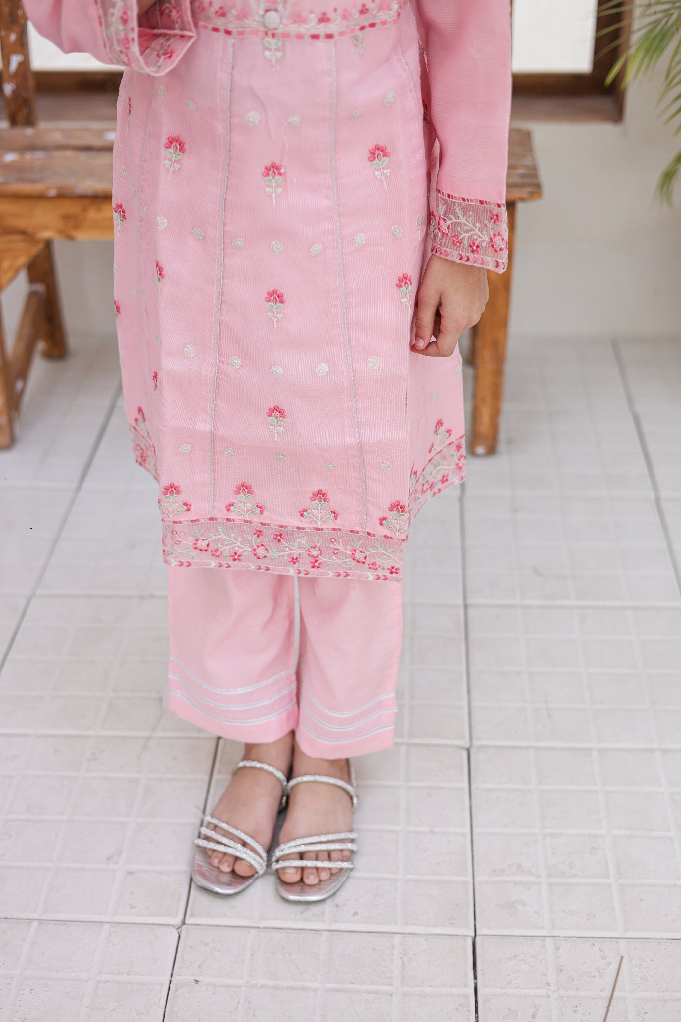 Person wearing a pink traditional outfit with floral patterns on a tiled floor.