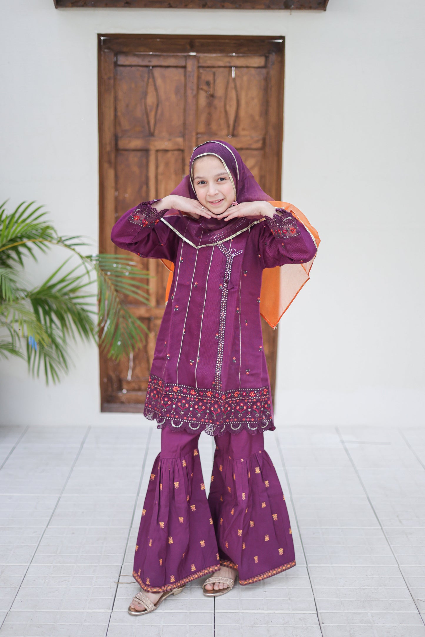 Person wearing a traditional purple outfit with a headscarf indoors.
