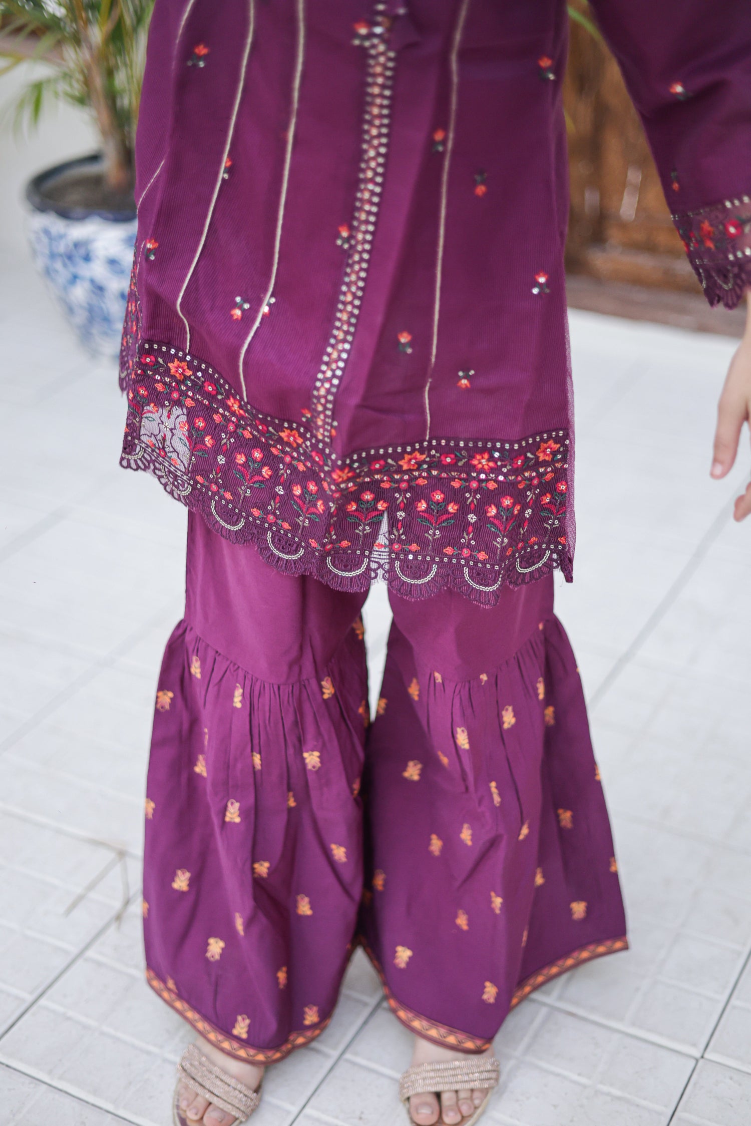 Purple traditional outfit with intricate patterns on a tiled floor.