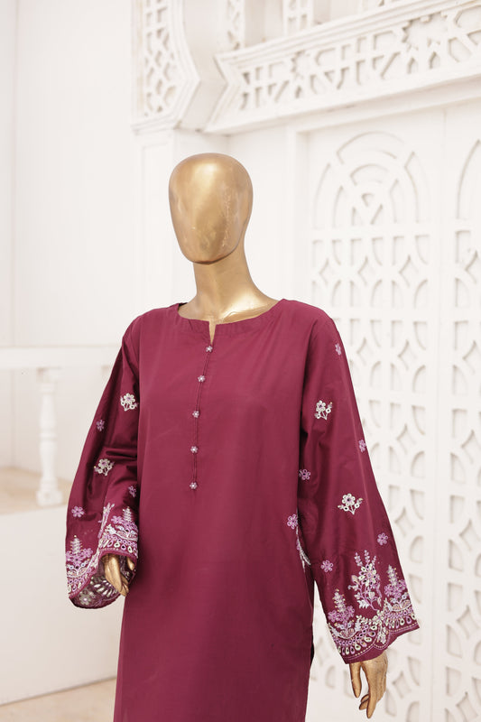 Maroon dress with floral patterns on a mannequin against a white decorative wall.