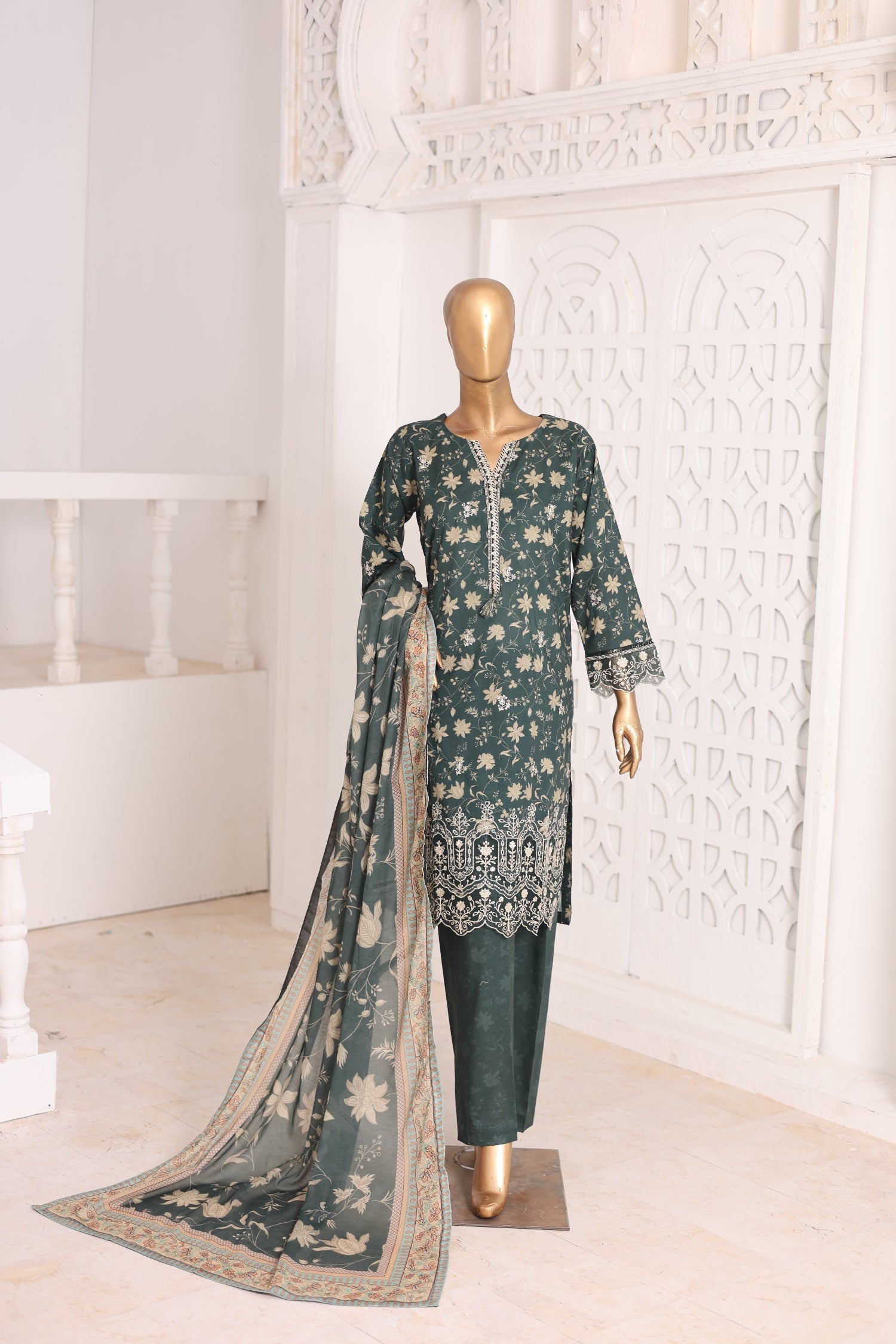 Mannequin wearing a green embroidered outfit with a matching dupatta in a white room.