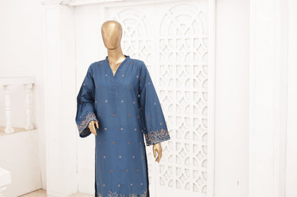 Blue dress with intricate patterns on a mannequin against a white decorative wall.