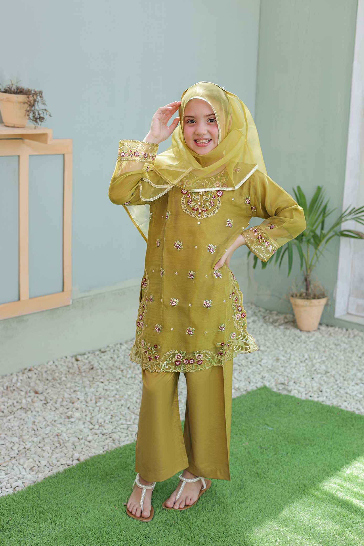 Woman wearing a yellow traditional outfit with a matching headscarf indoors.